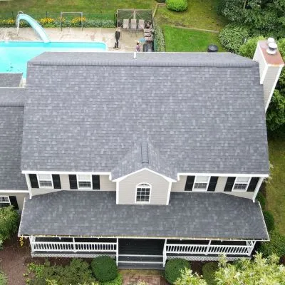 aerial view of house with mottled gray shingles and pool in the back yard