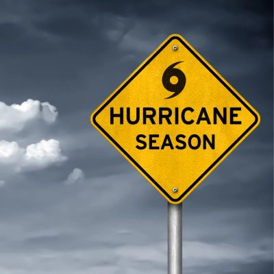Warning sign in front of stormy sky that says, "Hurricane Season"